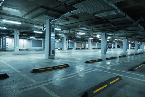 An empty underground parking garage with concrete floors, support columns, fluorescent lighting, and yellow parking space dividers stretches across multiple levels.RetryClaude can make mistakes. Please double-check responses.
